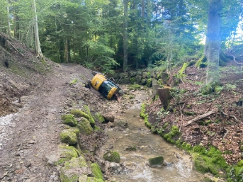 Bagger kippt zur Seite und landet im Bachbett 